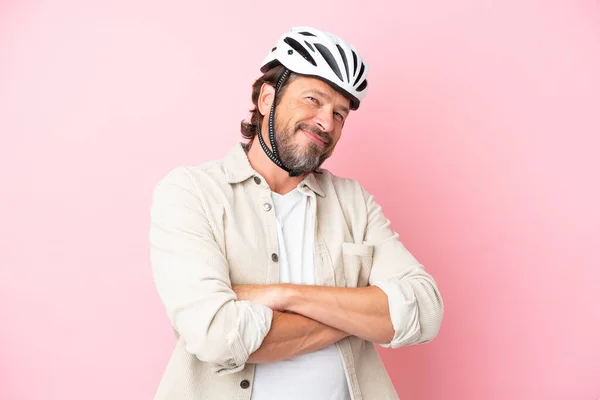 戴自行车头盔的高个子男子 粉色背景隔离 双臂交叉放在正面位置 — 图库照片