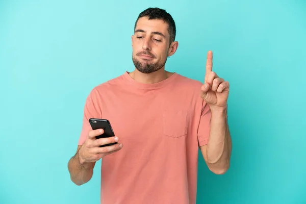 Genç Yakışıklı Beyaz Adam Mavi Arka Planda Cep Telefonu Parmak — Stok fotoğraf