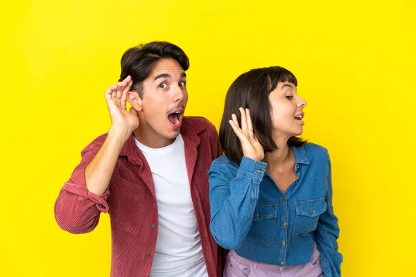 Jong Gemengd Ras Paar Geïsoleerd Gele Achtergrond Luisteren Naar Iets — Stockfoto