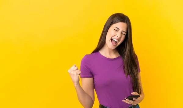 Adolescente Brasileña Chica Sobre Aislado Fondo Amarillo Con Teléfono Posición —  Fotos de Stock