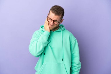 Mor arka planda diş ağrısı olan yakışıklı, beyaz bir adam.