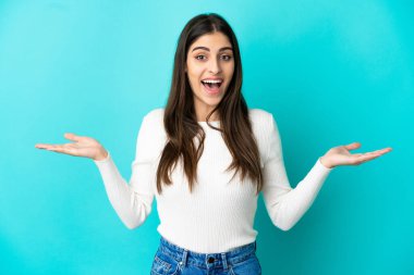 Yüzünde şok ifadesi olan mavi arka planda izole edilmiş beyaz bir kadın.