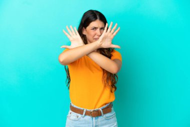 Mavi arka planda izole edilmiş genç beyaz kadın ellerini öne uzatıyor.