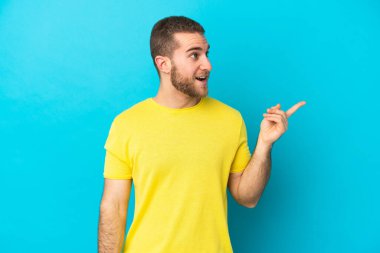 Genç, beyaz, mavi arka planda izole edilmiş genç bir adam çözümü bulmak için parmağını kaldırıyor.