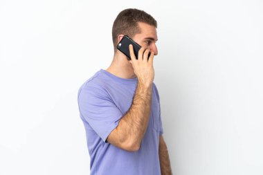 Beyaz arka planda izole edilmiş yakışıklı beyaz bir adam cep telefonuyla sohbet ediyor.