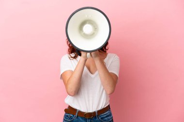 Pembe arka planda izole edilmiş genç bir kadın megafonla bir şey duyurmak için bağırıyor.