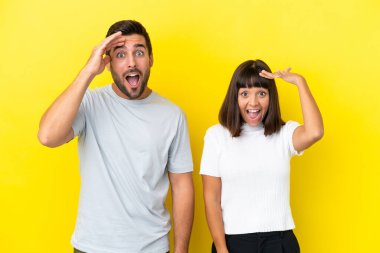 Sarı arka planda izole edilmiş genç çift bir şeyin farkına vardı ve çözüme ulaşmaya çalışıyor.