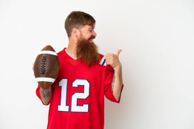 Beyaz arka planda ragbi oynayan Kafkasyalı genç adam bir ürünü sunmak için yan tarafı işaret ediyor.