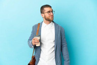 Kafkasyalı genç işadamı mavi arka planda izole edilmiş ve araştırılıyor.