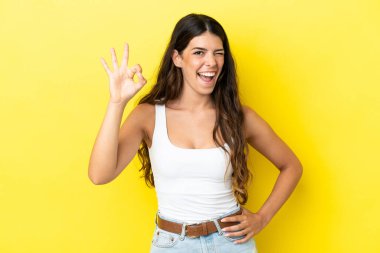 Sarı arka planda izole edilmiş beyaz kadın parmaklarıyla tamam işareti gösteriyor.