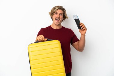 Genç sarışın adam, beyaz arka planda izole edilmiş. Tatilde, bavullu ve pasaportlu.