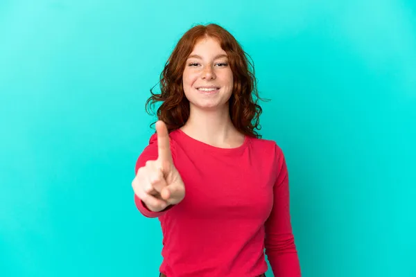 Adolescente Mujer Rojiza Aislada Sobre Fondo Azul Mostrando Levantando Dedo — Foto de Stock