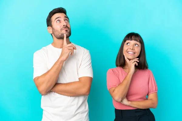 Jong Paar Geïsoleerd Blauwe Achtergrond Denken Een Idee Terwijl Opkijken — Stockfoto