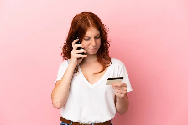 Tiener Roodachtige Vrouw Geïsoleerd Roze Achtergrond Kopen Met Mobiele Telefoon — Stockfoto