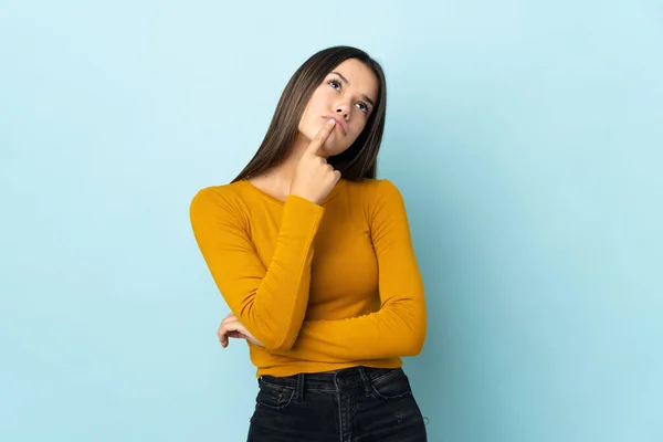 Adolescente Chica Aislada Sobre Fondo Azul Teniendo Dudas Mientras Mira —  Fotos de Stock