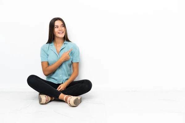 Adolescente Chica Sentada Suelo Apuntando Lado Para Presentar Producto — Foto de Stock