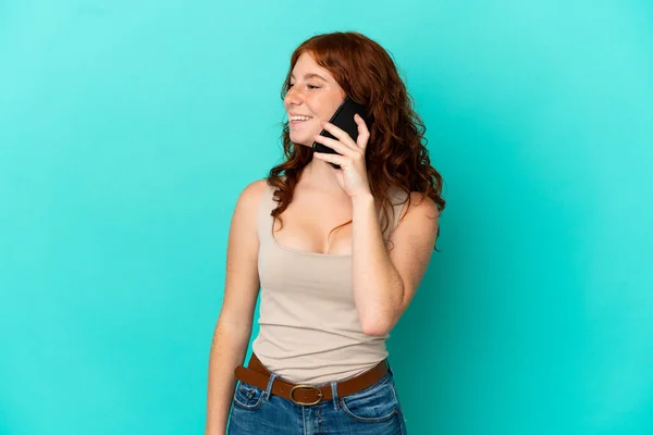 与蓝色背景隔离的少女红发女郎与手机对话 — 图库照片