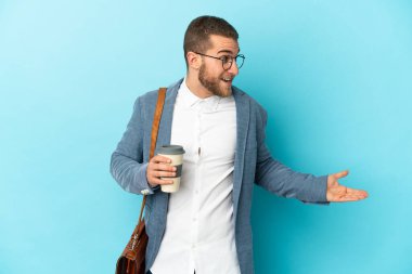 Kafkasyalı genç işadamı mavi arka planda, yana bakarken sürpriz bir ifadeyle izole edilmiş.