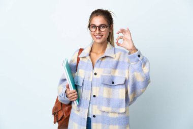 Beyaz arka planda izole edilmiş genç bir öğrenci iki eliyle tamam işareti gösteriyor.