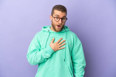 Mor arka planda izole edilmiş yakışıklı beyaz adam sağa bakarken şaşırmış ve şok olmuştu.