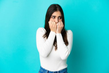 Mavi arka planda izole edilmiş beyaz bir kadın gergin ve korkmuş bir şekilde elleriyle suni teneffüs yapıyor.