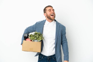 Beyaz arka planda izole edilmiş eşyalarla dolu bir kutuyu alırken genç beyaz adam hamle yapıyor.