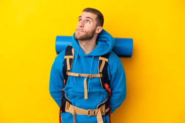 Sarı arka planda izole edilmiş büyük sırt çantalı beyaz bir dağcı.