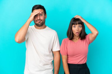 Mavi arka planda, şaşırmış ve şok olmuş bir yüz ifadesi olan genç bir çift.
