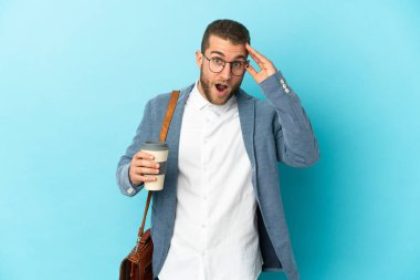 Kafkasyalı genç işadamı mavi arka planda, sürpriz bir ifadeyle izole edilmiş.