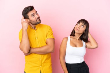 Pembe arka planda izole edilmiş genç bir çift kafalarını kaşırken bir fikir düşünüyorlar.