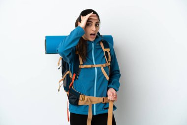 Arka planda büyük bir sırt çantası olan genç dağcı yan tarafa bakarken sürpriz jest yapıyor.