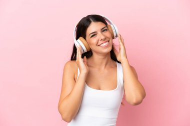 Pembe arka planda izole edilmiş beyaz bir kadın müzik dinliyor.