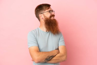 Kırmızımsı beyaz adam pembe arka planda izole edilmiş mutlu ve gülümsüyor.