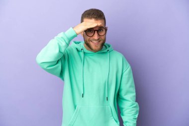 Mor arka planda soyutlanmış yakışıklı beyaz bir adam bir şeye bakmak için uzaklara bakıyor.