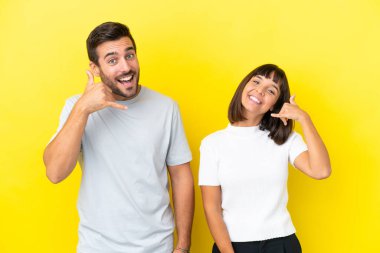 Sarı arka planda izole edilmiş genç bir çift telefon jesti yapıyor. Bana geri dönüş işareti ver.