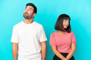 Genç çift mavi arka planda yalnız, gergin ve korkmuş.