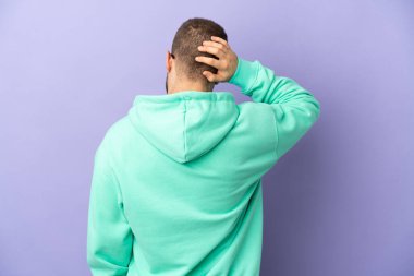Mor arka planda izole edilmiş yakışıklı beyaz adam arka planda ve düşünüyor.