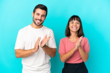 Genç çift mavi arka planda bir konferansta sunumdan sonra alkış tutuyor.