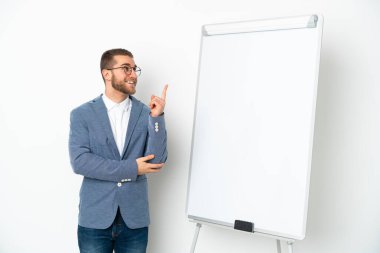 Beyaz arka planda izole edilmiş beyaz panoda sunum yapan genç iş kadını harika bir fikre işaret ediyor.