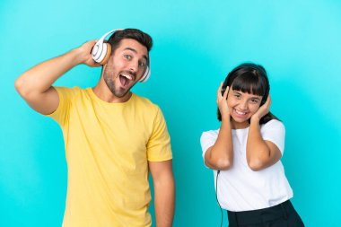 Genç çift mavi arka planda izole edilmiş müzik dinliyor.