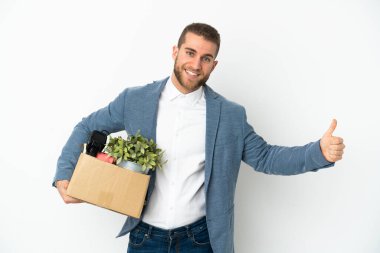 Beyaz arka planda izole edilmiş eşyalarla dolu bir kutuyu kaldırırken beyaz tenli genç harekete geçiyor.