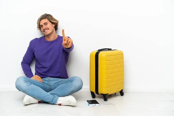 Bavullu Genç Sarışın Adam Yerde Oturuyor Parmağını Kaldırıyor — Stok fotoğraf