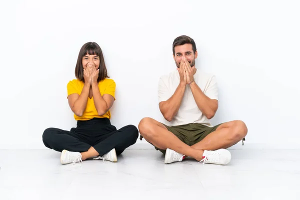 Casal Jovem Sentado Chão Isolado Fundo Branco Sorrindo Muito Enquanto — Fotografia de Stock