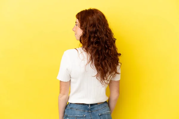 Adolescente Mulher Avermelhada Isolado Fundo Amarelo Posição Traseira Olhando Para — Fotografia de Stock