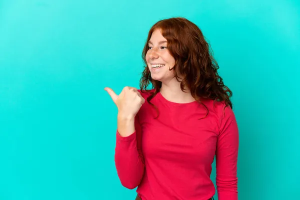 Tiener Roodachtige Vrouw Geïsoleerd Blauwe Achtergrond Wijzend Naar Zijkant Naar — Stockfoto