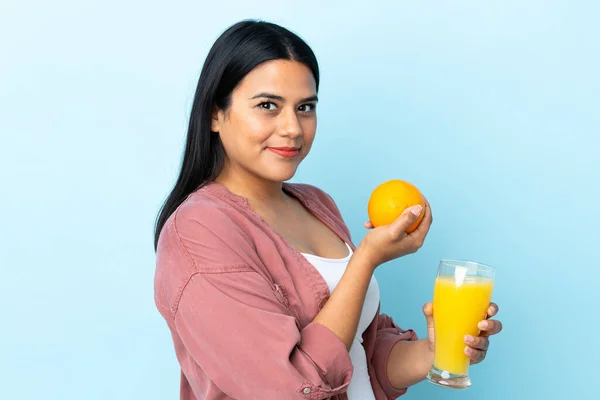 Junge Lateinische Frau Isoliert Auf Blauem Hintergrund Mit Einer Orange — Stockfoto