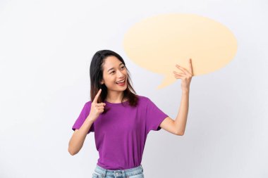 Beyaz arka planda izole edilmiş genç Vietnamlı kadın boş bir konuşma balonu tutuyor ve düşünüyor.