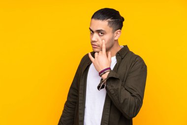 Asyalı yakışıklı adam sarı arka planda izole edilmiş, yana bakıyor ve gülümsüyor.