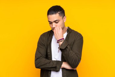 Asyalı yakışıklı adam sarı arka planda izole edilmiş ve yukarı bakıyor.