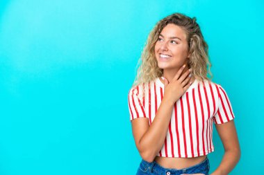 Kıvırcık saçlı kız mavi arka planda izole edilmiş gülümserken yukarı bakıyor